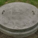 Okrągła betonowa pokrywa zbiornika septycznego na trawie