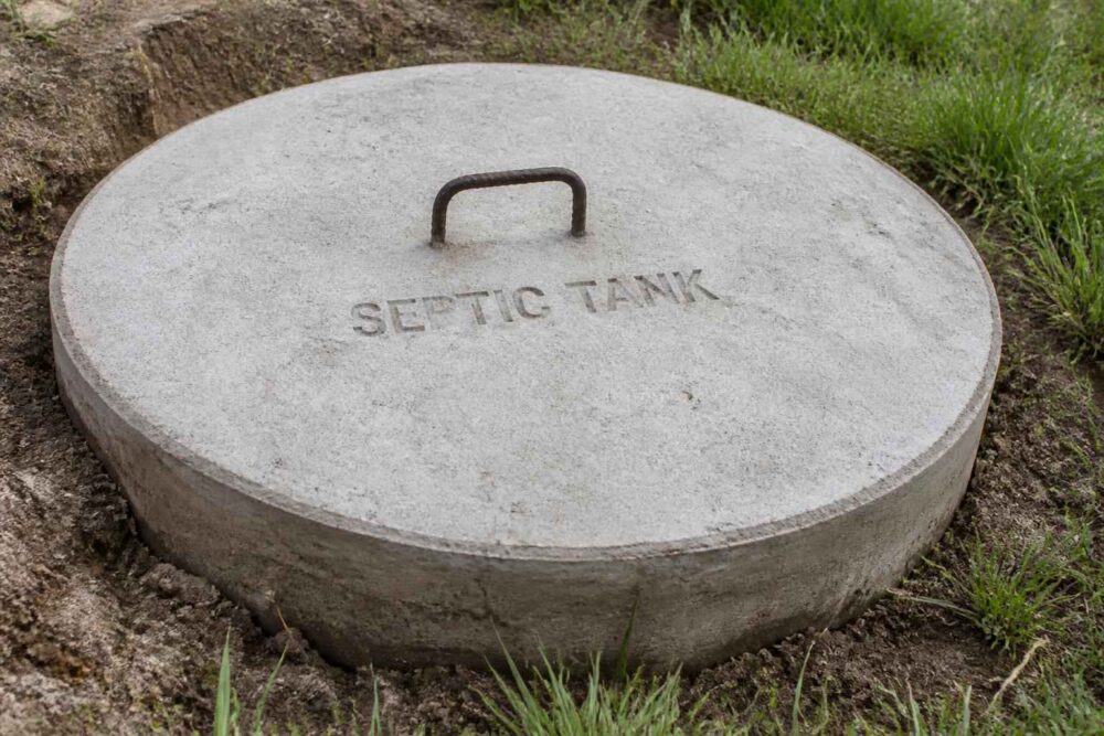 Okrągła płyta włazu szamba Betonowa płyta z uchwytem i napisem SEPTIC TANK w ziemi i trawie