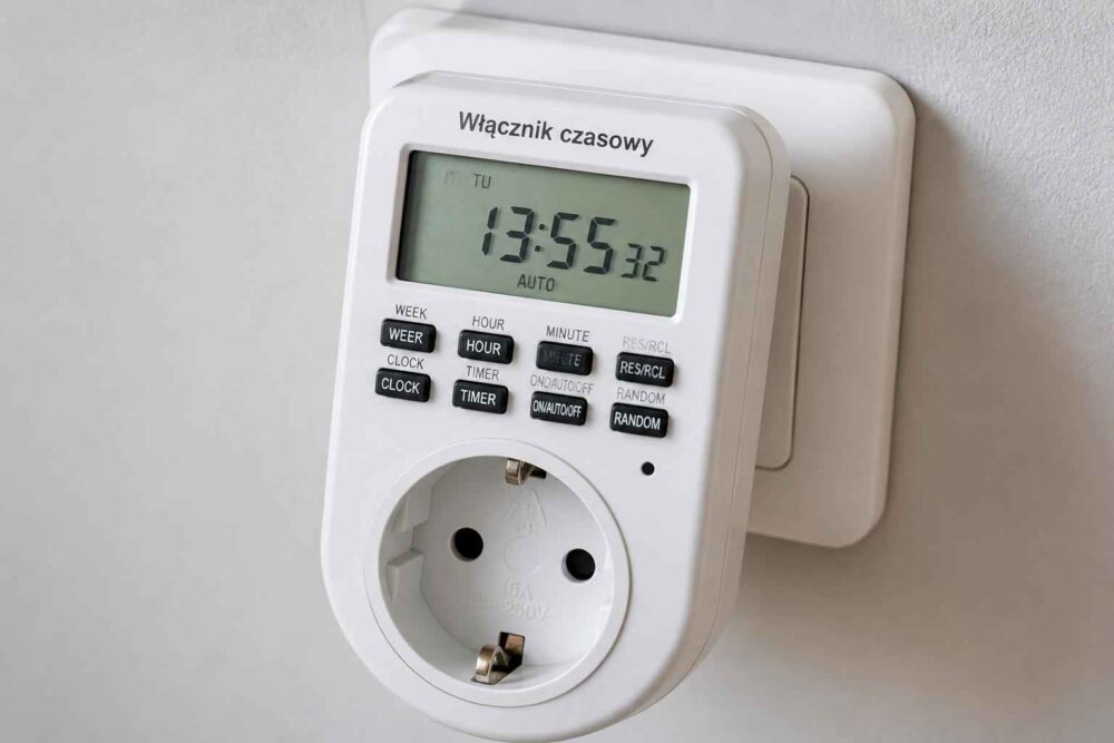 Biały programator czasowy z wyświetlaczem i gniazdem elektrycznym na ścianie