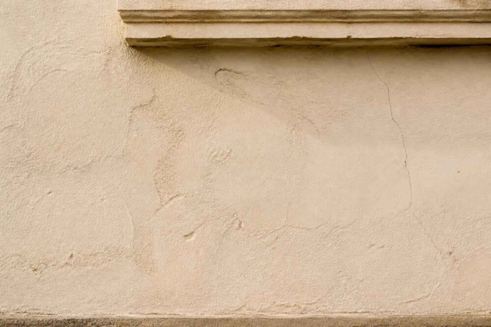 Jasna, spękana ściana budynku z ozdobnym gzymsem u góry