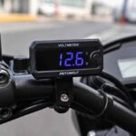Cyfrowy woltomierz na kierownicy motocykla wskazuje napięcie 12,8 V